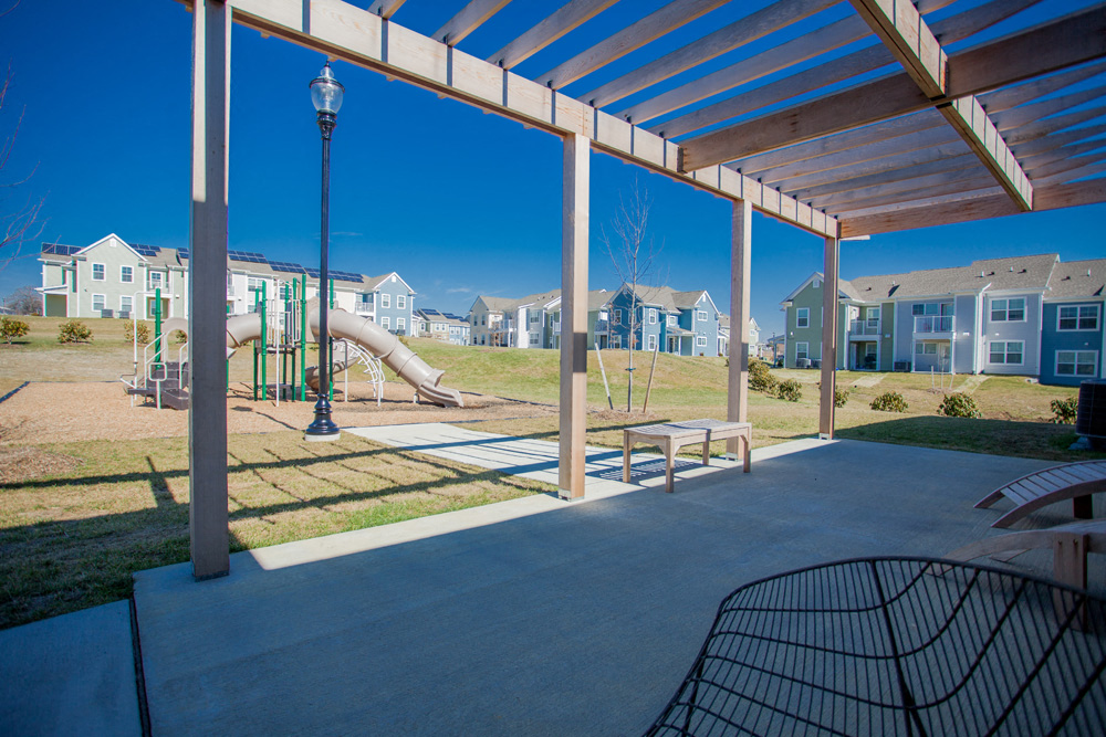 a playground with a slide and benches under a pavilion
