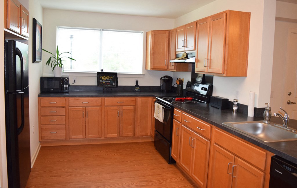 a kitchen with wooden cabinets and a black counter top