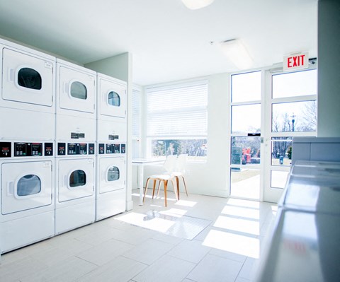 a laundry room with white washers and dryers and a door to the outside