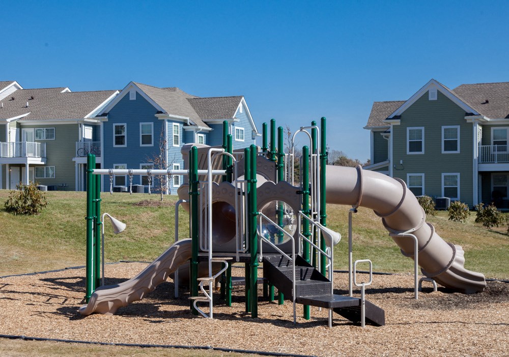 a playground with a slide and a tube in front of houses