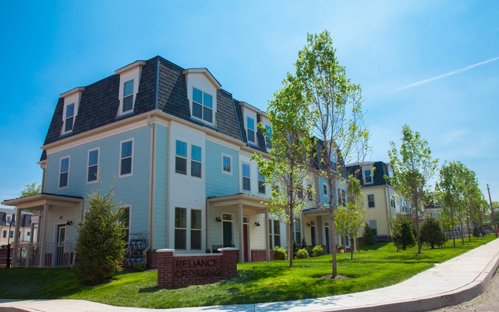 a row of houses with blue roofs and green grass and trees