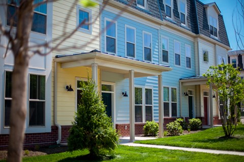 a row of houses with blue and white siding and a green lawn