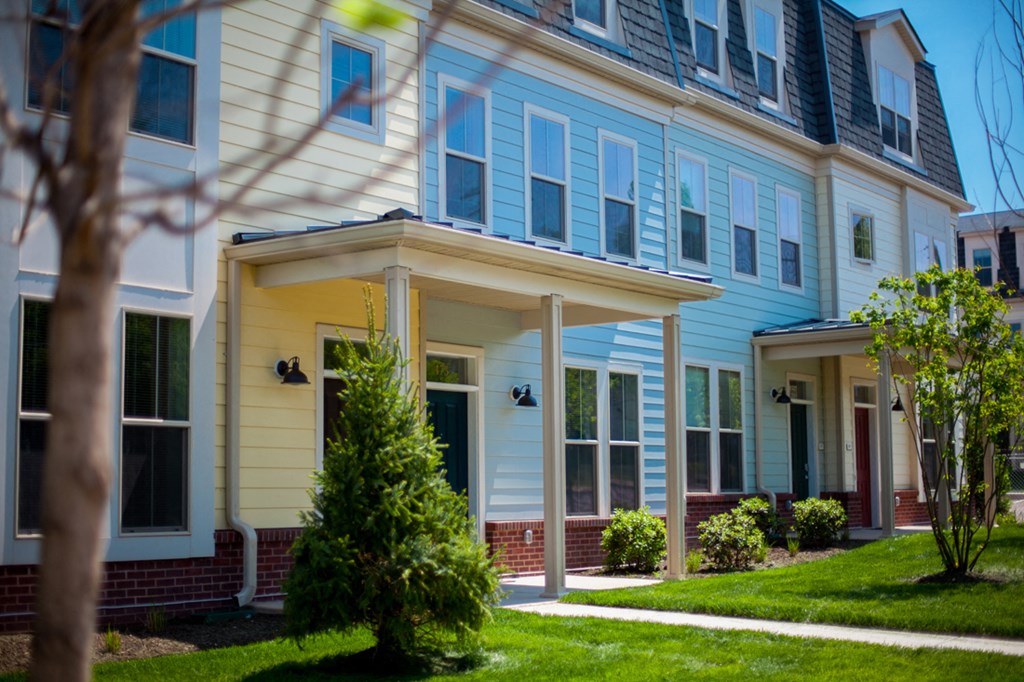a row of houses with blue and white siding and a green lawn