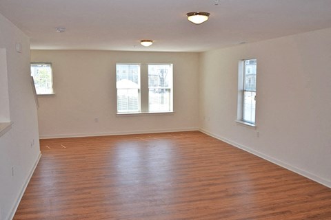 an empty living room with wood floors and windows