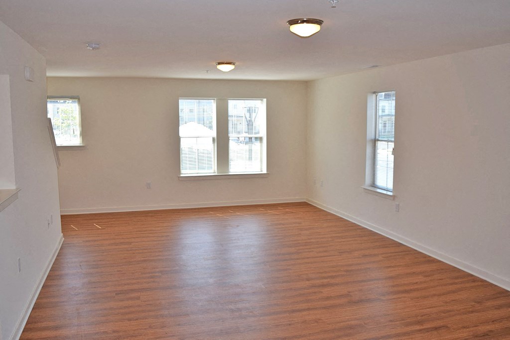 an empty living room with wood floors and windows