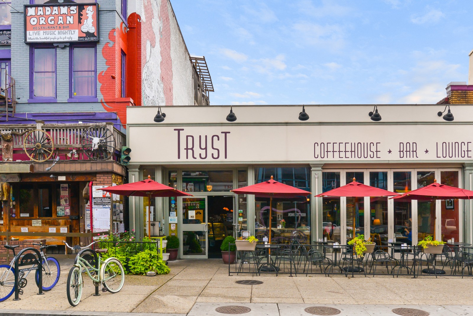 the outside of a coffee shop with tables and umbrellas