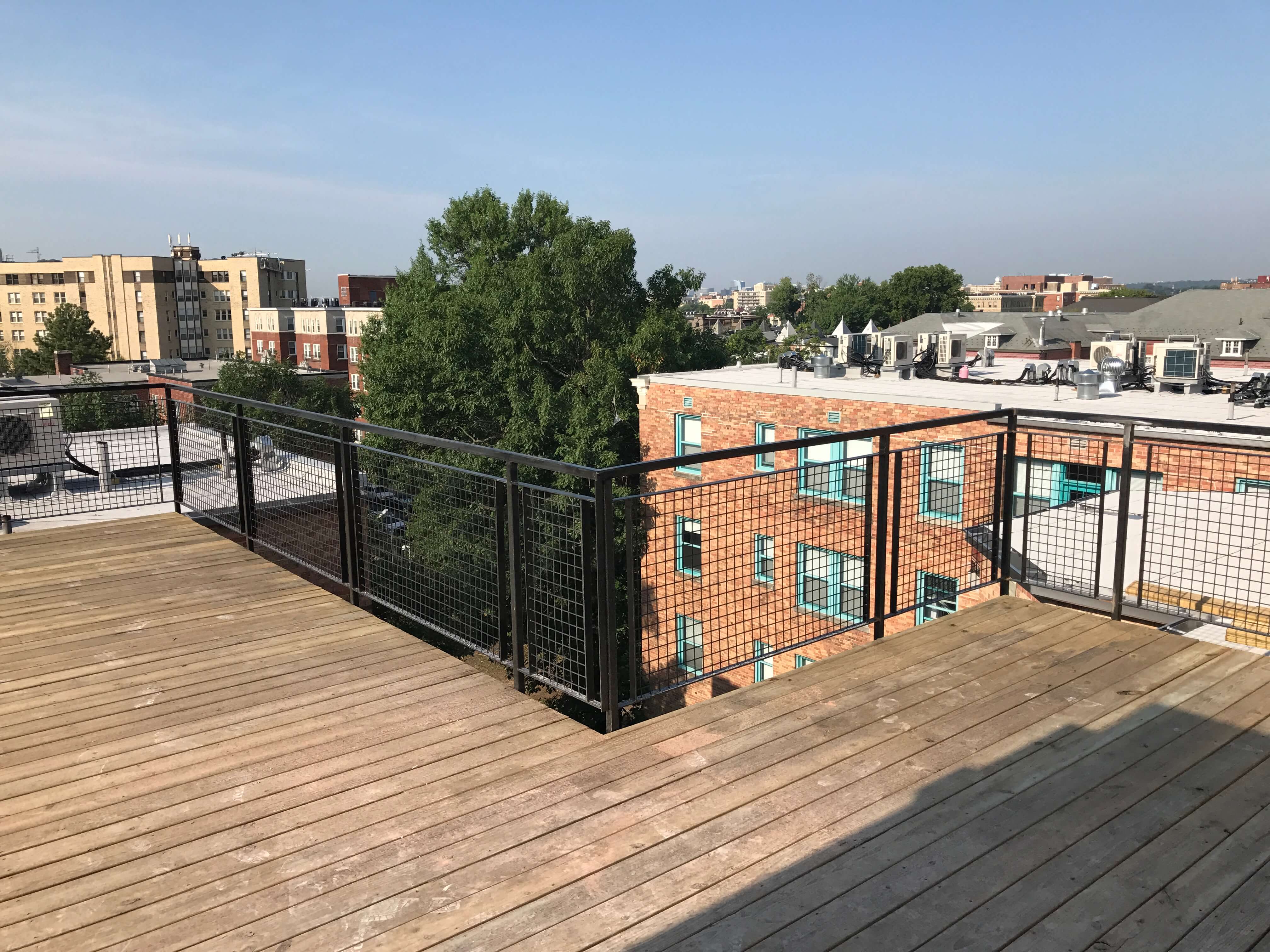 a wooden deck with a black railing on top of a roof