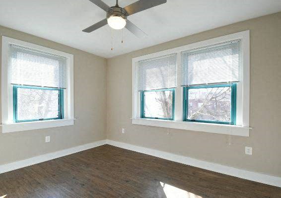 an empty room with a ceiling fan and three windows