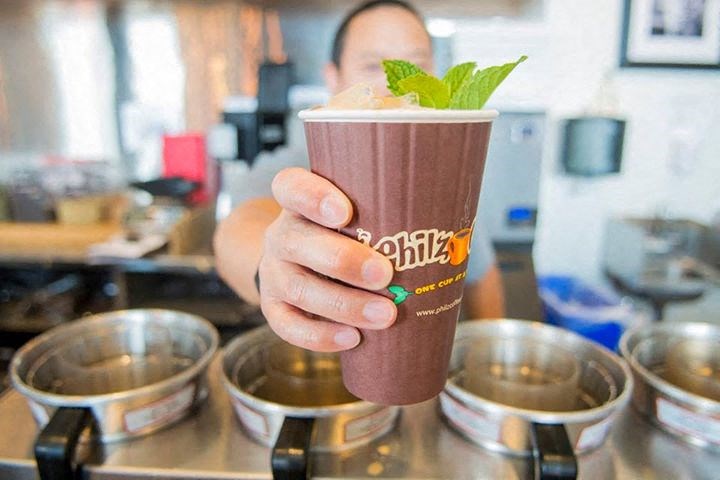 a hand holding a chocolate milkshake