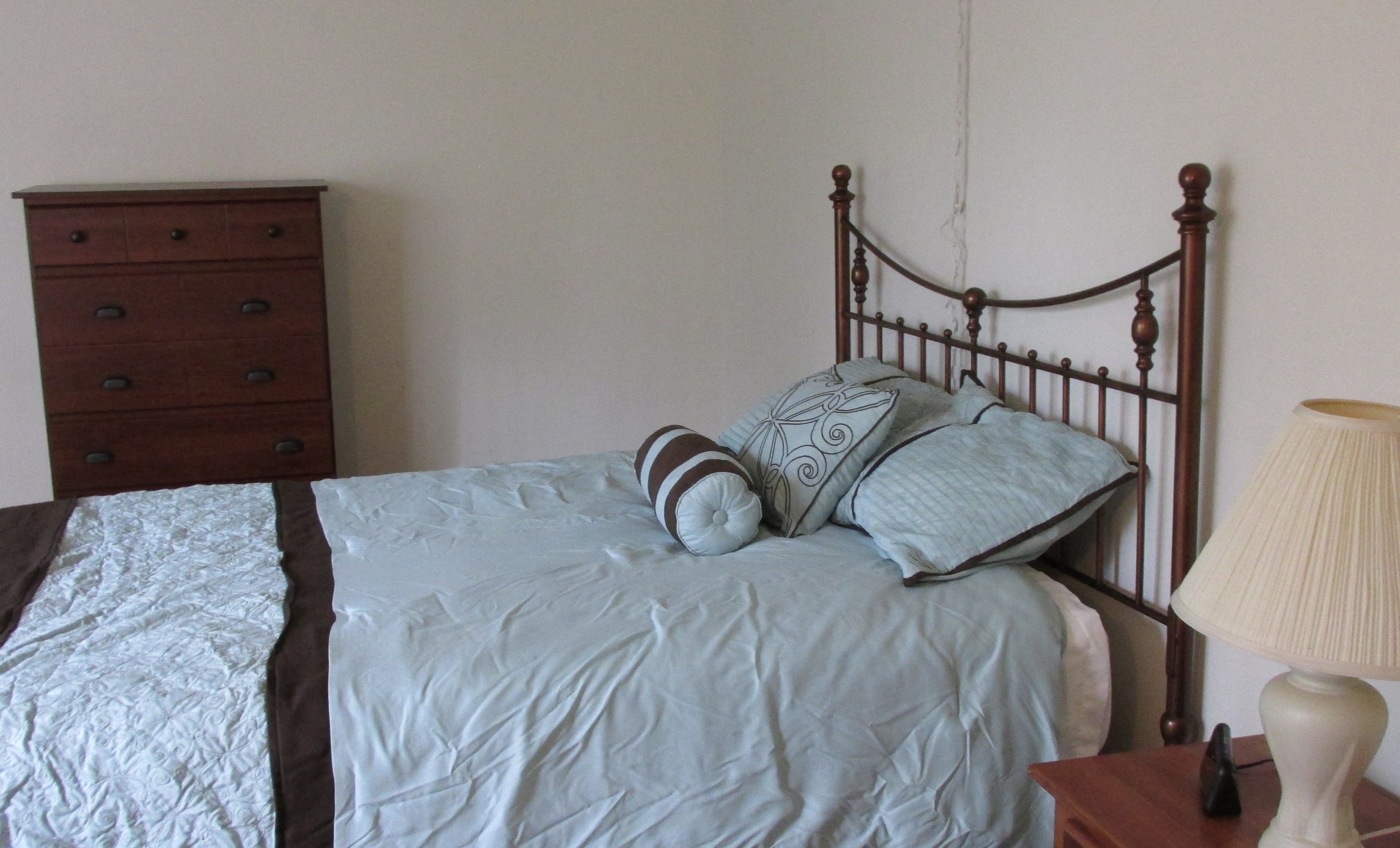 the master bedroom has a queen sized bed and a dresser