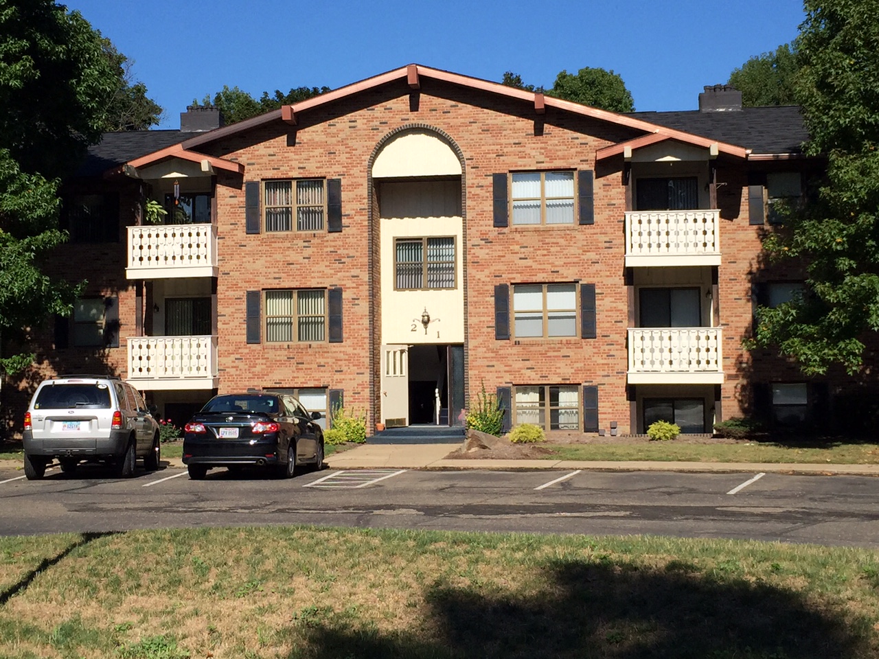 an apartment building with cars parked in a parking lot