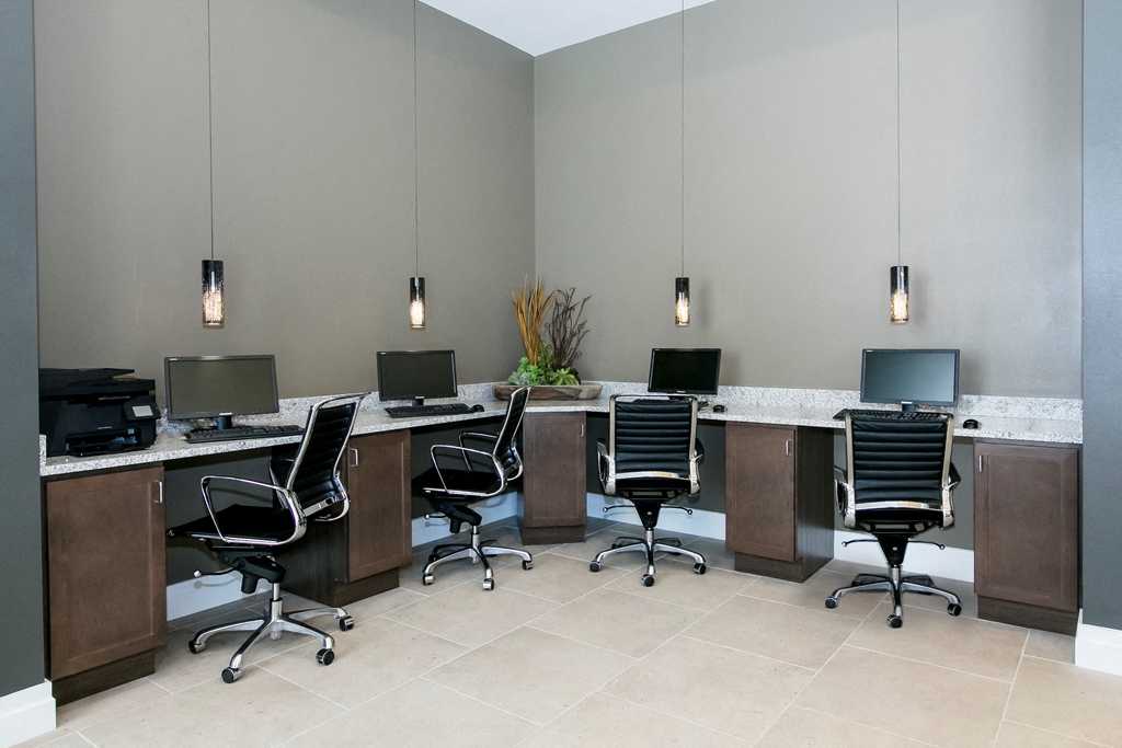 a conference room with four desks with computers and chairs