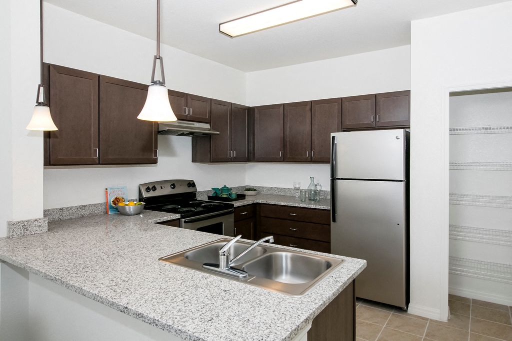 a kitchen with granite counter tops and a stainless steel refrigerator