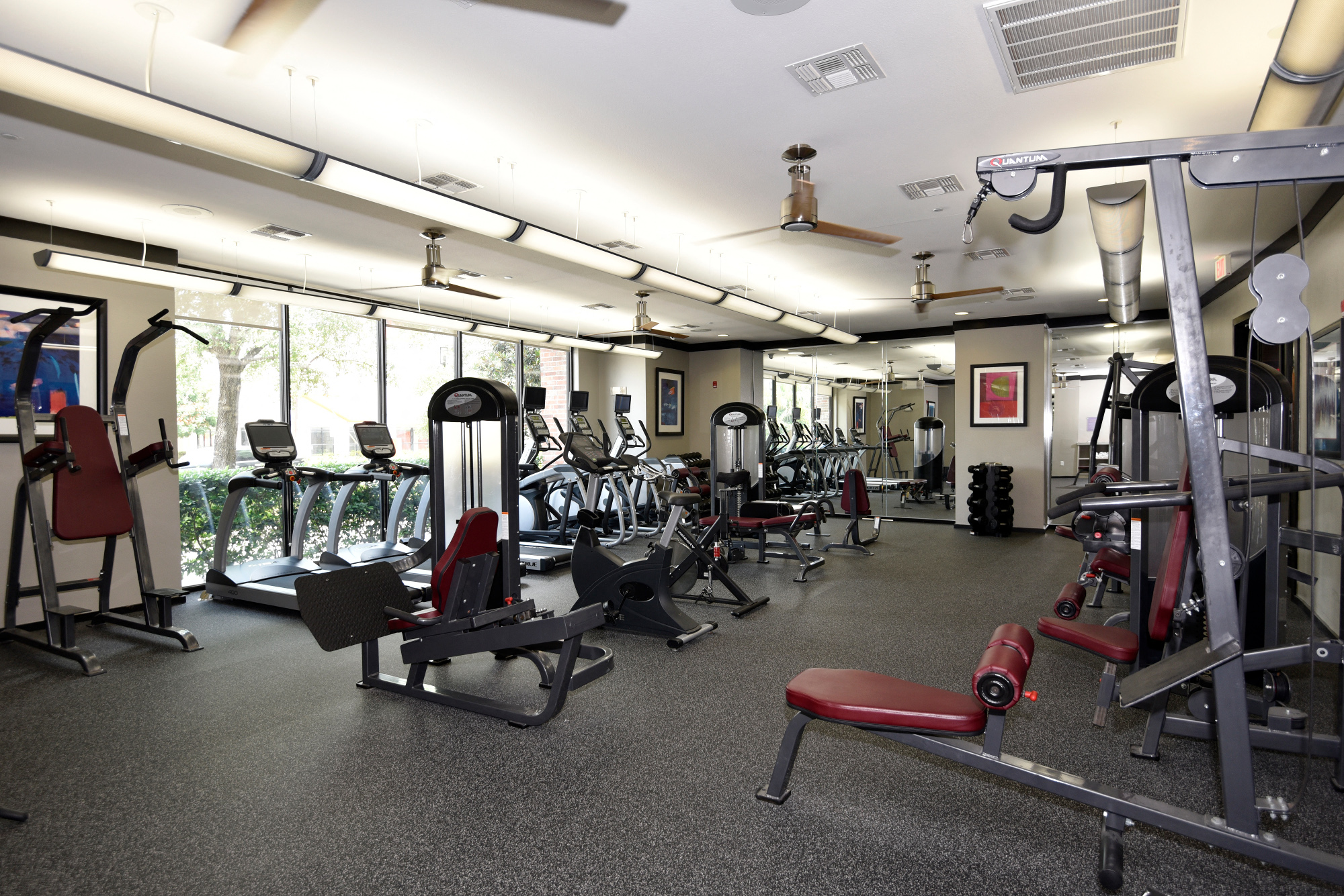 a gym with various exercise equipment on the floor and windows