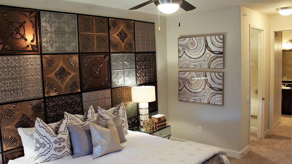 a bedroom with a bed and a wall of canvases