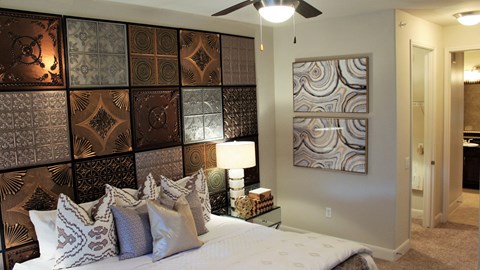 a bedroom with a bed and a wall of canvases