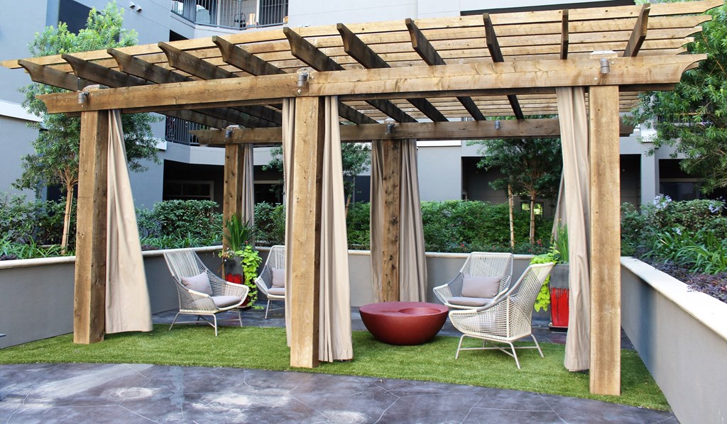 a pergola with chairs and a table on a lawn