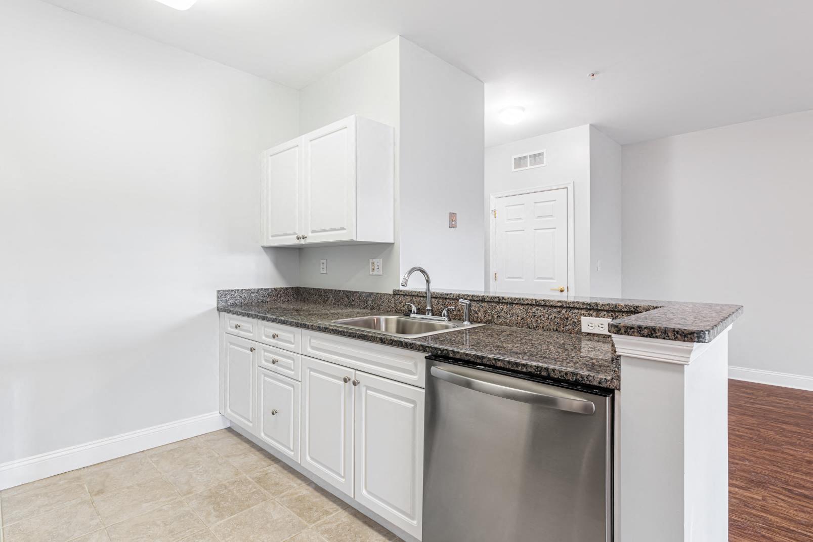 a kitchen with white cabinets and granite counter tops and a stainless steel dishwasher