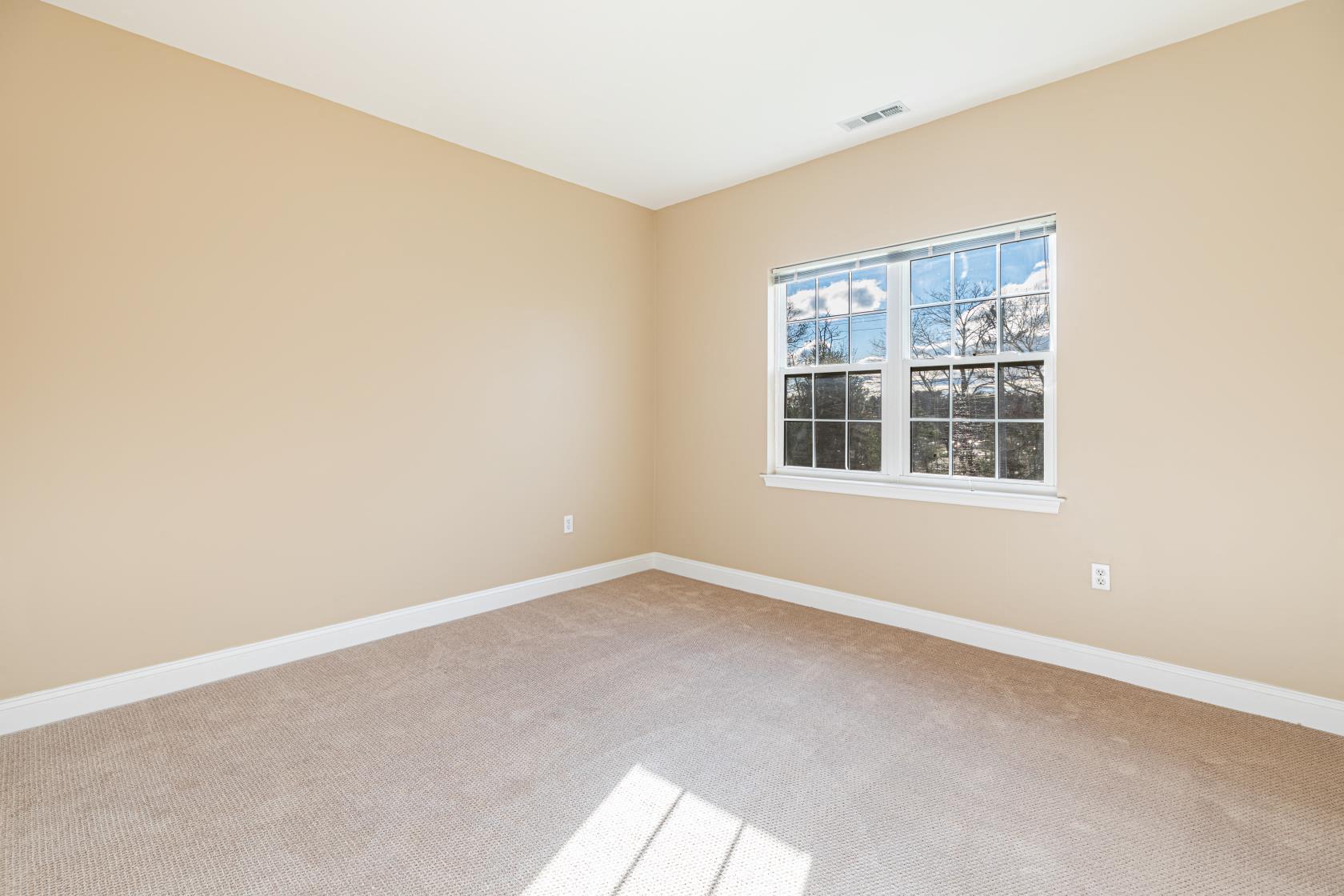 an empty room with a window and carpet