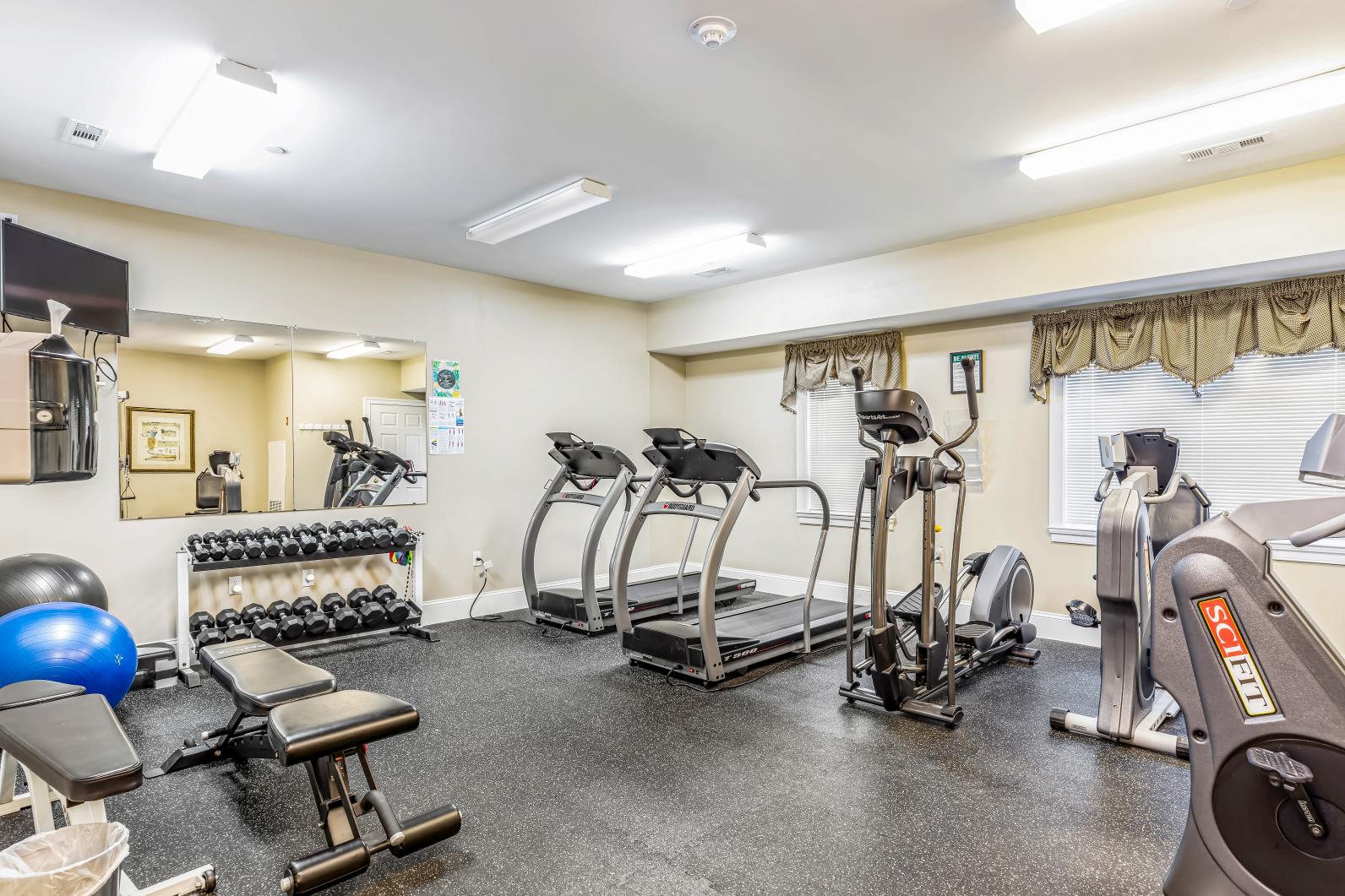 a gym with cardio equipment and weights on the floor