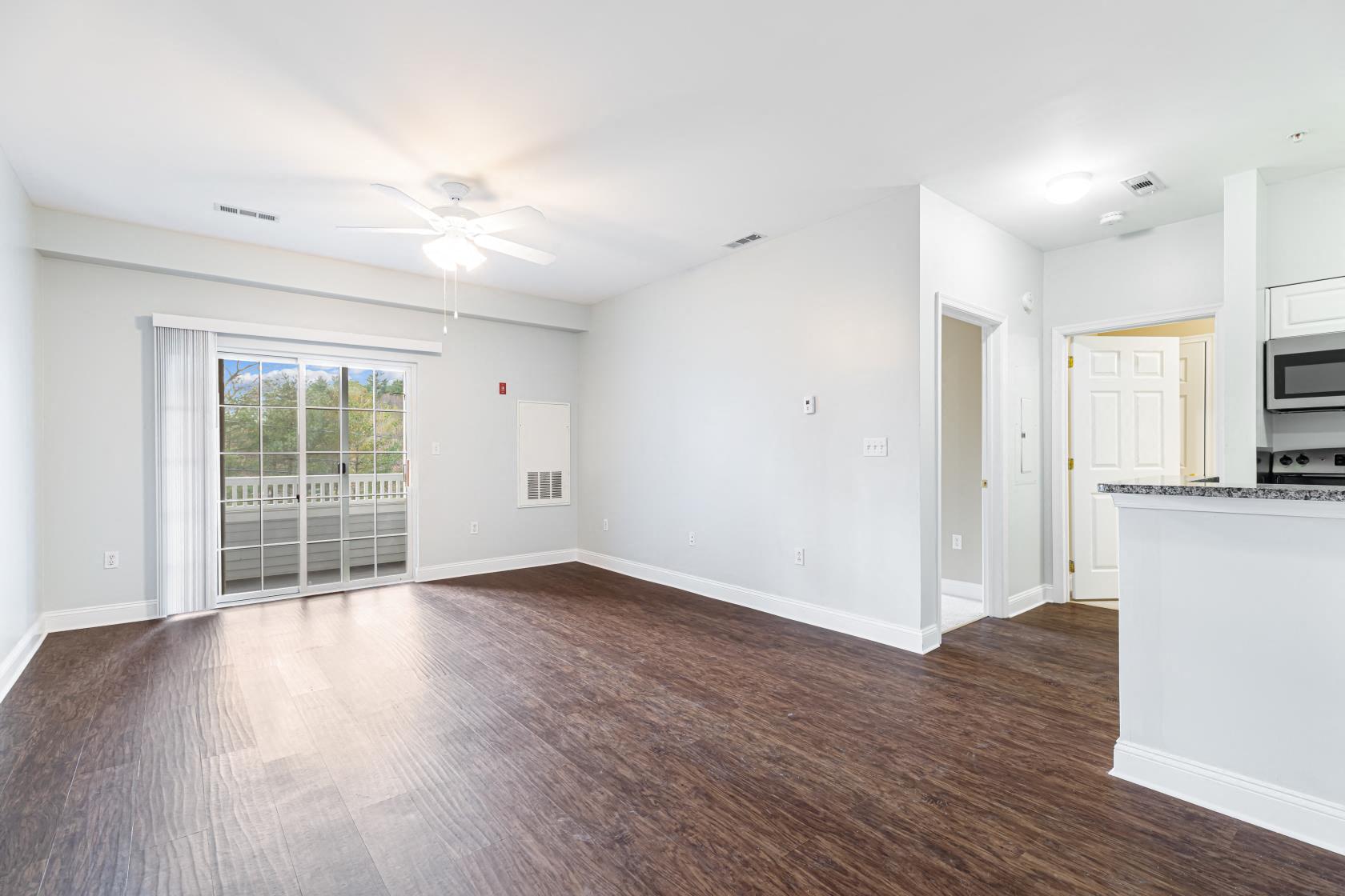 an empty living room and kitchen with wood flooring and a window
