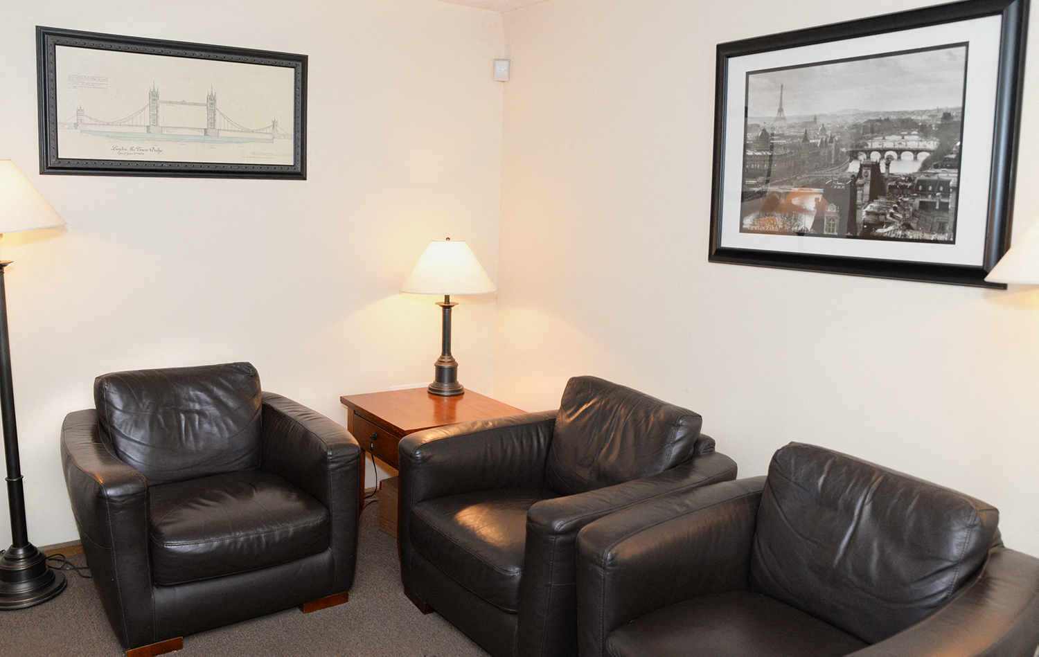a small living room with leather chairs and pictures on the wall