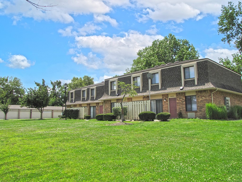 a brick house with a green lawn in front of it