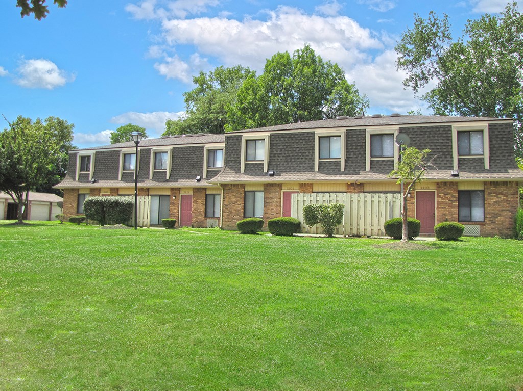 an apartment building with a green lawn in front of it