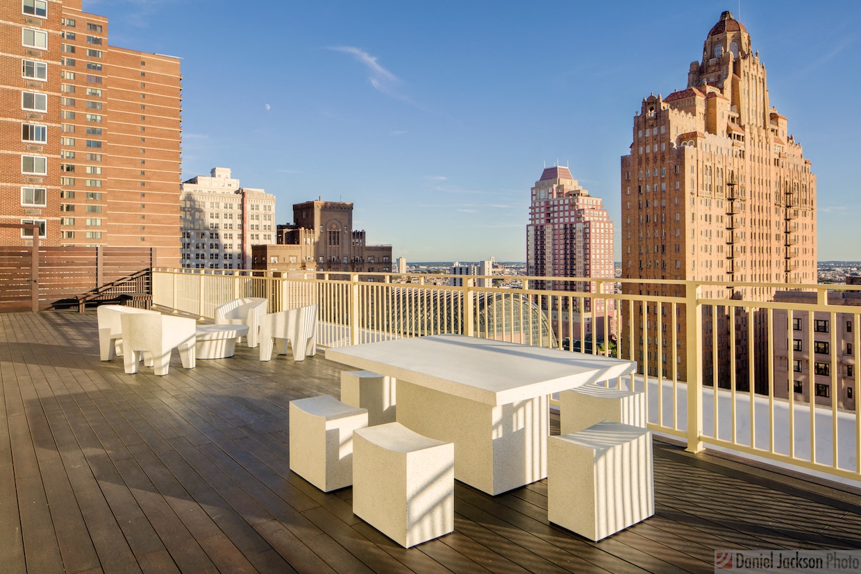 a roof deck with a table and chairs and a view of the city