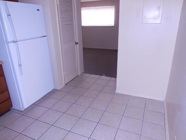 a kitchen with a white refrigerator and a tiled floor