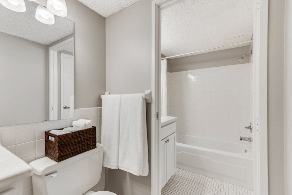 White bathroom with bright lights and the camera facing the bathtub and shower