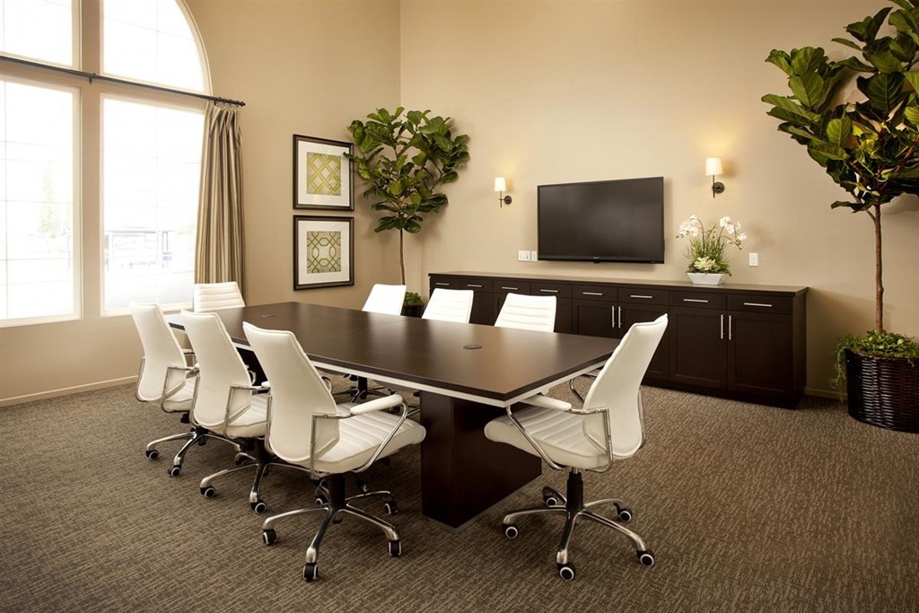 a conference room with a table and chairs and a television