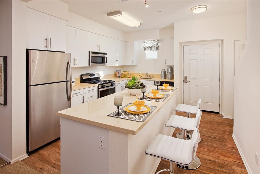 a kitchen with a long counter top and a stainless steel refrigerator