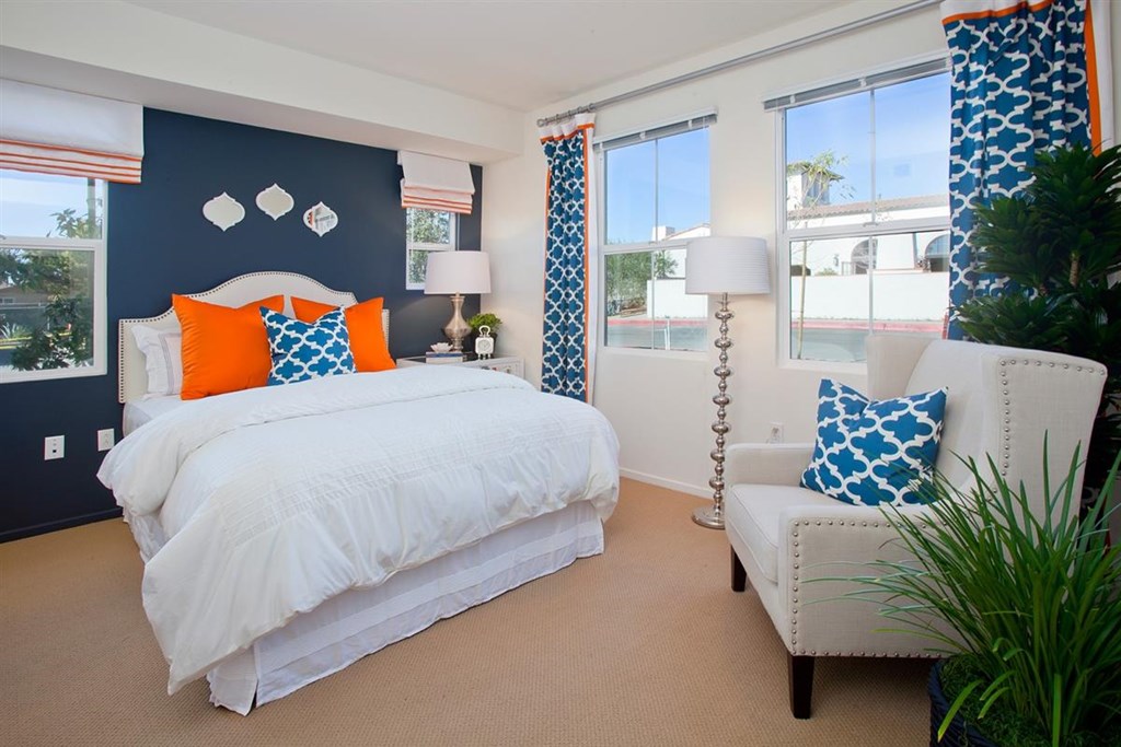 a blue and white bedroom with orange and blue pillows