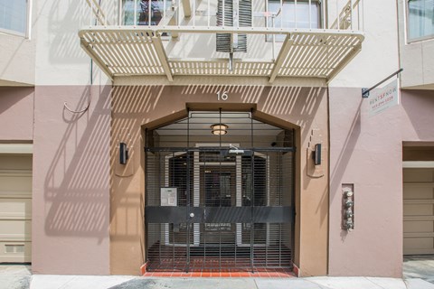 A building with a pink facade has a large gate in front of it.