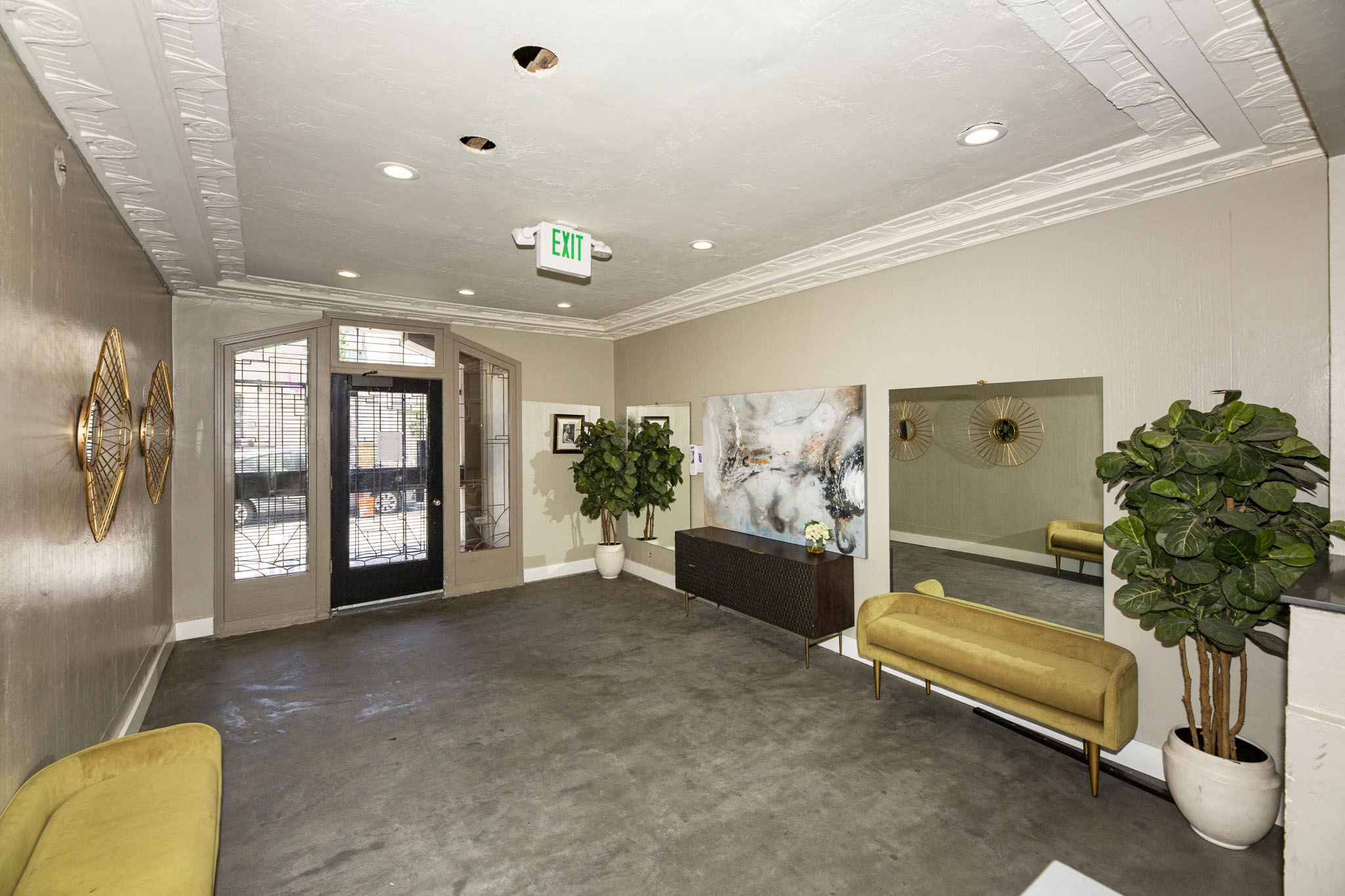 A well-lit waiting room with a yellow sofa and a large painting on the wall.