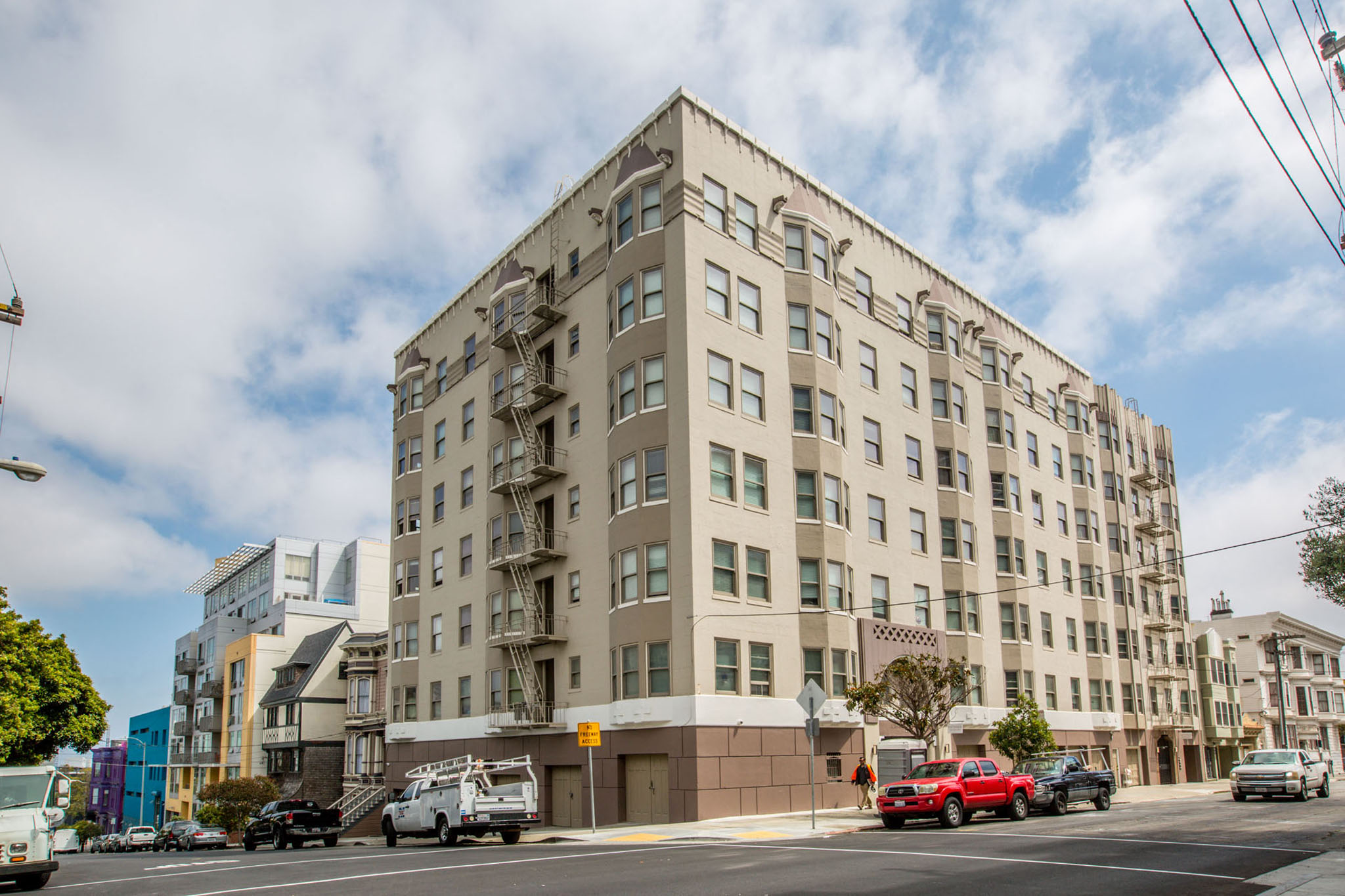 A large beige building with a grey roof and a fire escape on the side.