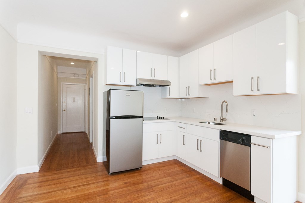 A kitchen with white cabinets and a stainless steel refrigerator.