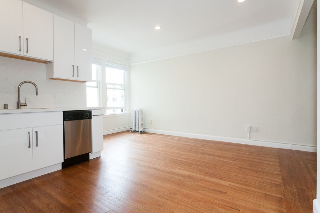 A kitchen with white cabinets and a wooden floor.