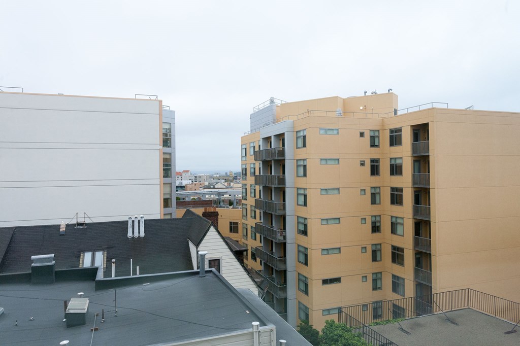 A view of a cityscape with buildings of different heights and a cloudy sky.