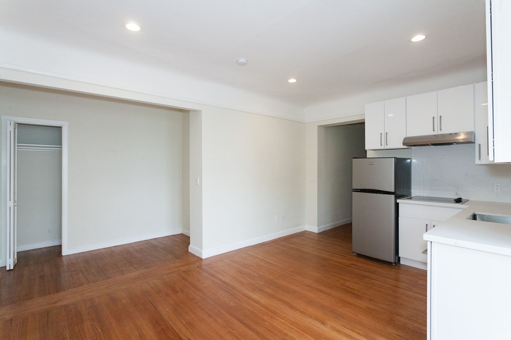 A kitchen with white cabinets and a wooden floor.