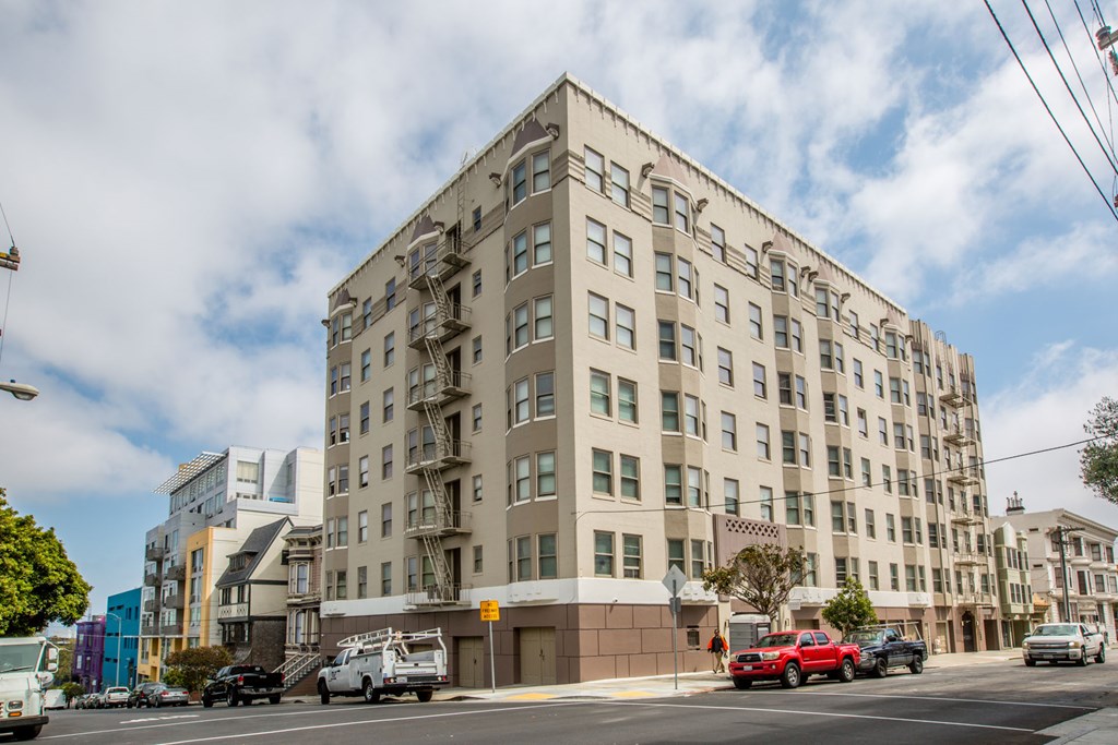 A large beige building with many windows and a fire escape on the side.