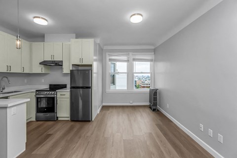 A kitchen with white cabinets and a black fridge.