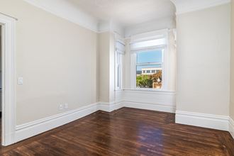 an empty room with wood floors and a window