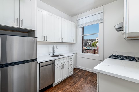 A kitchen with white cabinets and a stainless steel refrigerator.