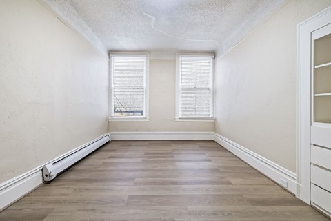 A room with wooden floors and a window with blinds.