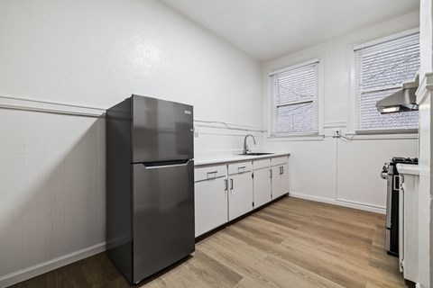 A kitchen with a black fridge and wooden floors.