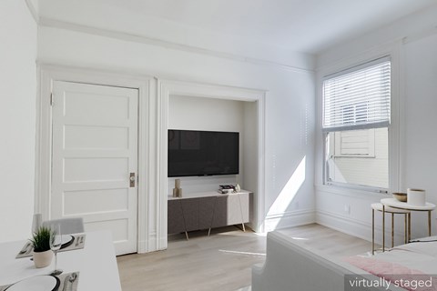 A white room with a television and a bed.