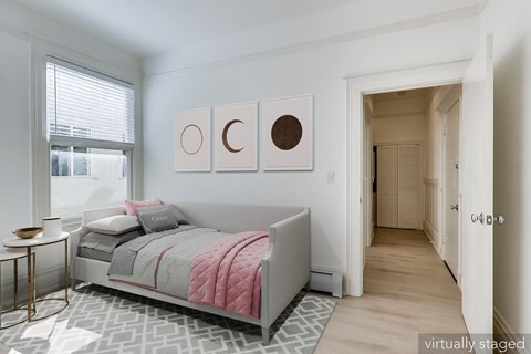A bedroom with a bed, a nightstand, and a window.
