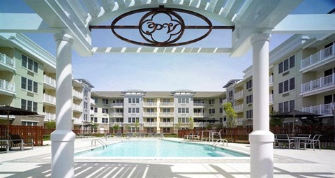 A pool area with a white pergola and a logo on it.